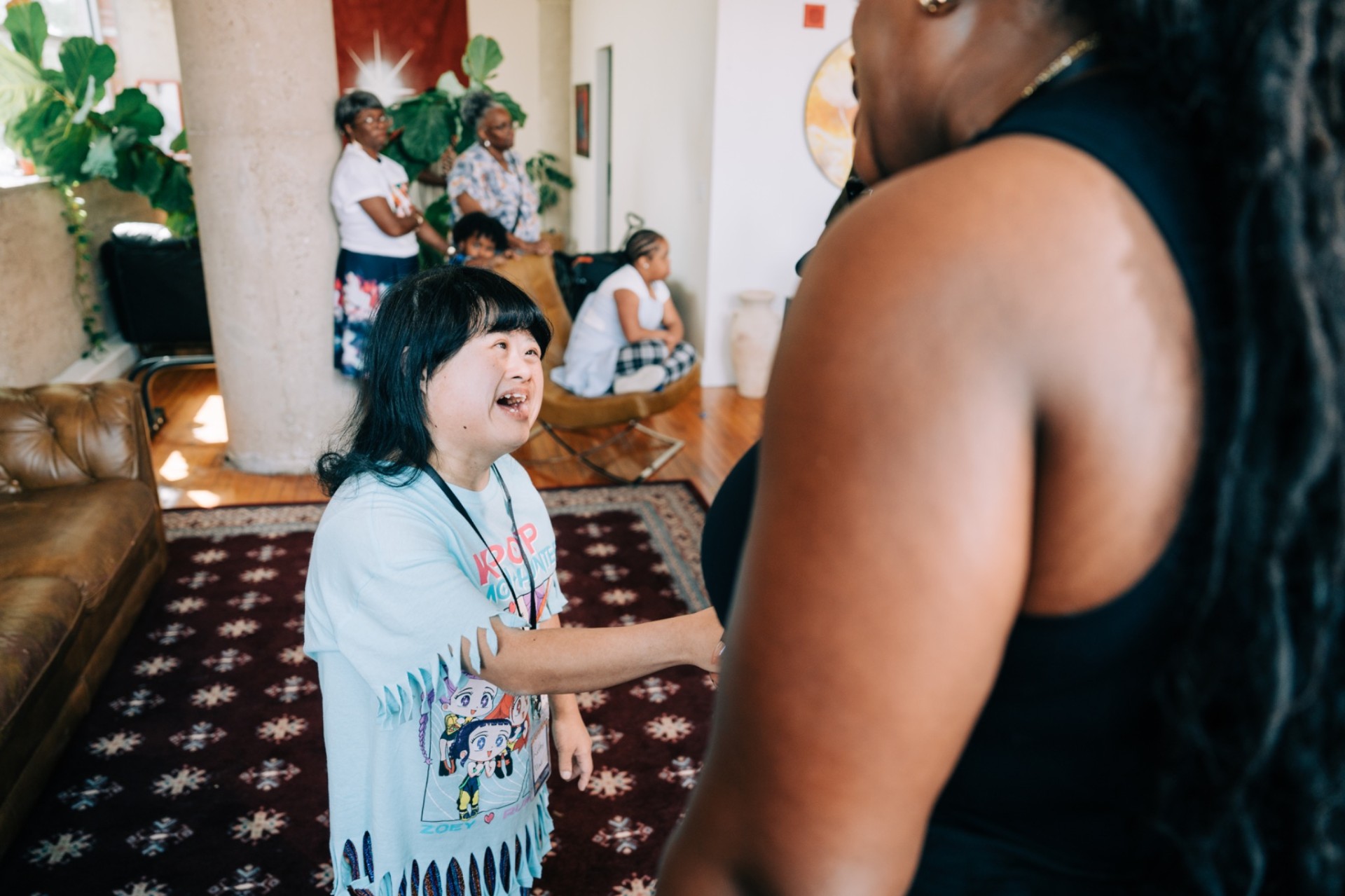 A young woman with Down syndrome shaking hands with a collaborator at an indoor Third Legacy gathering
